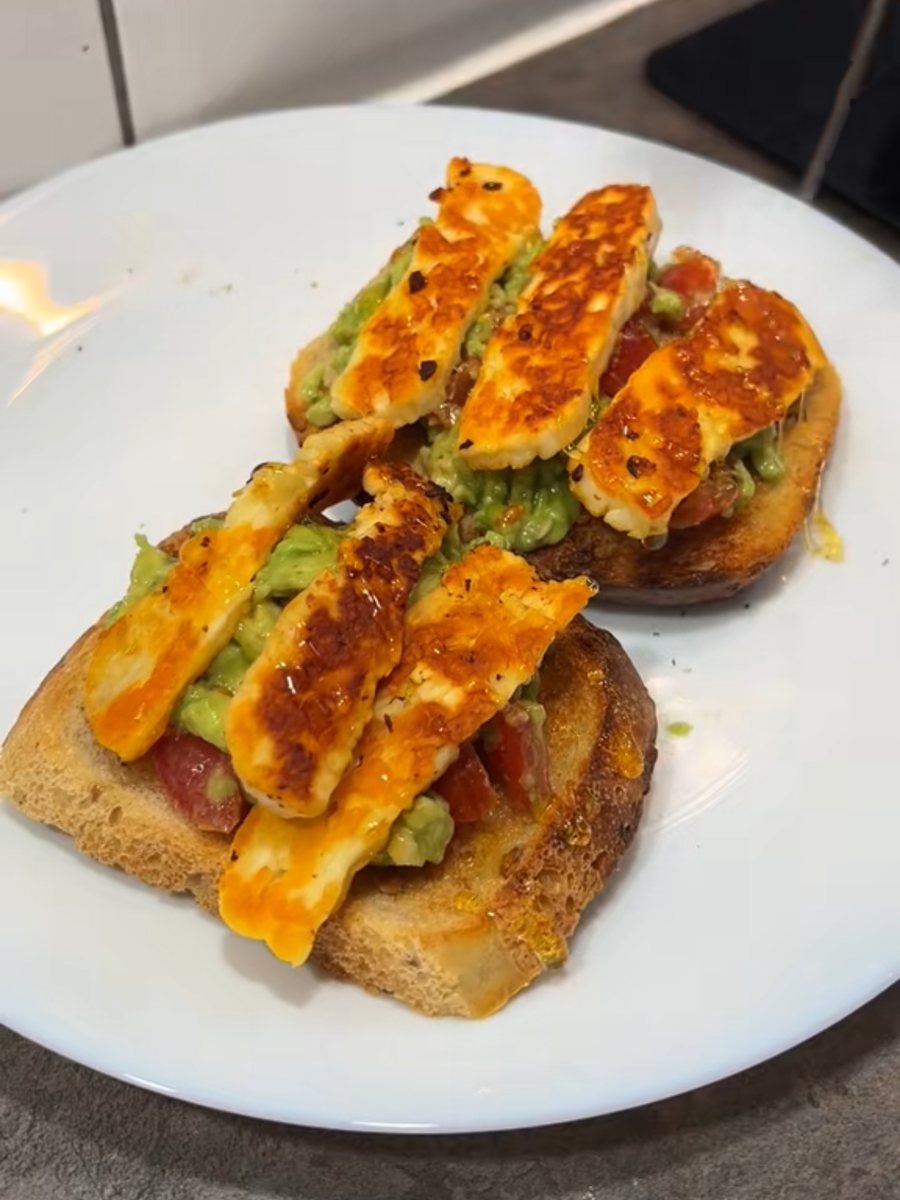 Two slices of sourdough with smashed avocado, cherry tomatoes and chilli-oil-fried halloumi